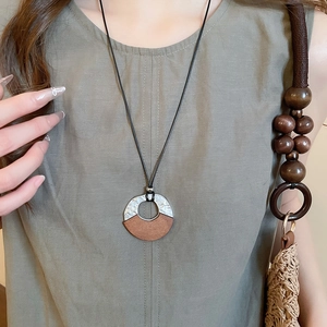 Close-up of a vintage geometric wooden necklace with hammered silver metal on linen top