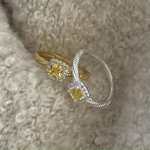 Macro view of gold and silver twisted rings featuring yellow square-cut halo gemstones