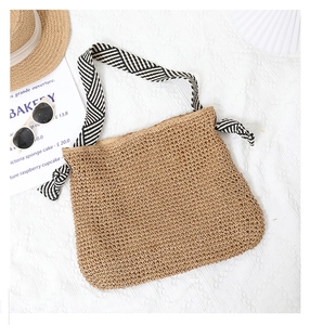 Close-up of woven straw handbag with striped handles and bow detail in a resort setting