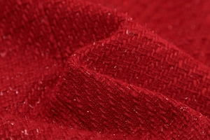 Macro shot of red tweed knit texture showing detailed woven fabric of the cardigan
