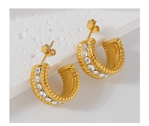 Macro detail of gold C-shaped twisted rope earrings featuring central zircon inlays