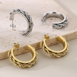 Macro detail of gold and silver twisted texture C-shape earrings on stone display