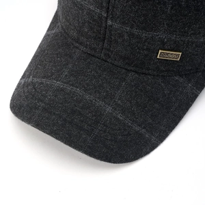 Detailed macro view of dark grey wool blend fabric and gold metal logo on winter cap