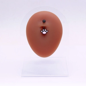 Détail d'un piercing de nombril noir avec pendentif patte rose sur un modèle en silicone
