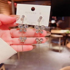 Detalle de pendientes de mariposa en plata S925 con borlas largas de cristal brillante