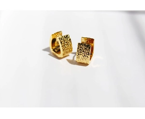 Close-up of gold-plated hoop earrings featuring unique hammered metal texture detail