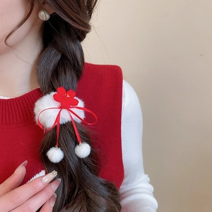 Detail of red plush floral hair scrunchie with cute white fur balls and ribbon accents