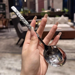 Handheld stainless steel soup spoon with a unique hammered texture handle and polished head