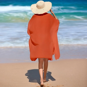 Détail de la tunique de plage orange vif avec fente latérale et chapeau de paille tressé