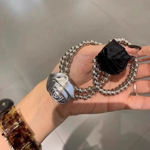 Élastique à perles avec d'élégantes breloques fleurs de rose en métal argenté et tissu noir