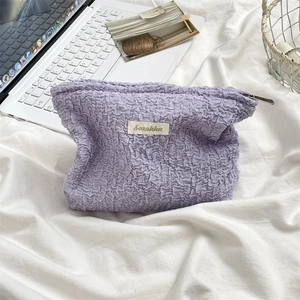 Detail of light purple seersucker makeup bag with a woven label and metallic zipper