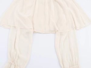 Detailed view of cream chiffon blouse featuring elastic smocked waist and soft pleated sleeves