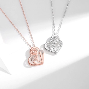 Macro shot of rose gold and silver heart pendants with zircon-encrusted rose details