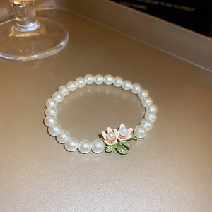 Macro detail of freshwater pearl bracelet with exquisite floral charms and gold plating