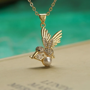 Gold-plated hummingbird necklace with sparkling zircon wings and a white pearl pendant