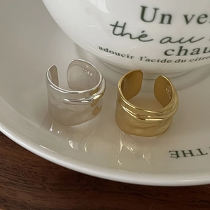 Minimalist S925 sterling silver wide open rings in gold and silver finishes on a ceramic plate