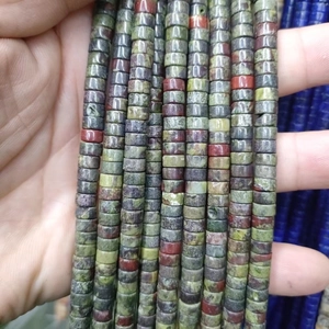 Macro shot of 3x6mm spacer beads showing natural green and red stone textures for DIY jewelry