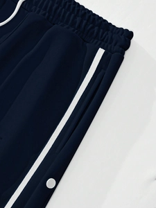 Detail of navy blue joggers with white side stripes and metallic snap buttons