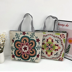 Detail of bohemian canvas tote bag featuring vibrant floral embroidery and striped handles