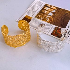 Detailed close-up of wide open bangles with irregular hollow lava texture in gold and silver