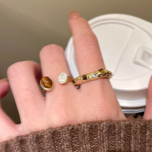 Detail view of tiger eye and zircon rings worn with a cozy autumn aesthetic