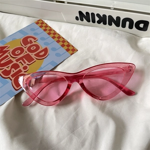 Detailed shot of pink cat-eye sunglasses on stylish white fabric and music decor