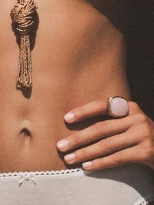 Detailed view of pink crystal ring and gold tassel necklace on a vintage aesthetic background