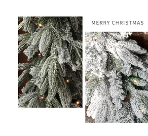 Close-up of artificial green pine needles with snow flocking and warm LED lights