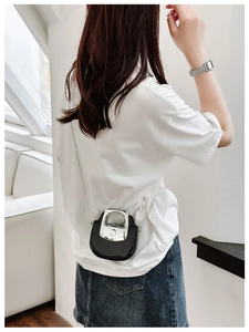 Mini black U-shaped saddle bag with silver horseshoe handle shown on model in casual wear