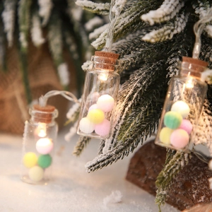 Detail of LED wishing bottles with colorful fur balls on a snowy Christmas tree
