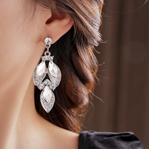 Close-up of silver flower drop earrings with sparkling leaf-shaped crystals on a model