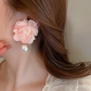 Close-up of pink fabric flower earrings with a large white round pearl drop on a model