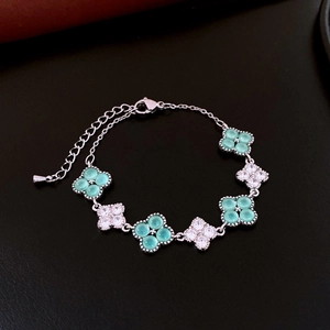 Detail of silver chain bracelet with green stones and sparkling zircon clover charms