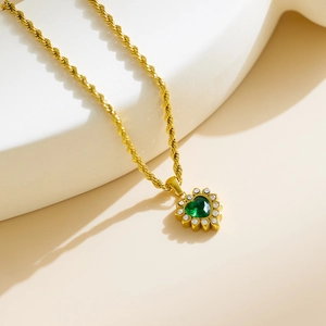 Golden heart pendant necklace with green gemstone and white crystals on twisted chain