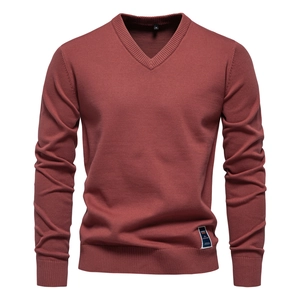 Close-up of V-neck neckline and ribbed cuffs on brick red men's cotton knit sweater