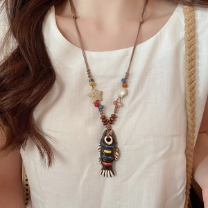 Detail of fish ceramic pendant with starfish beads on a vintage bohemian necklace