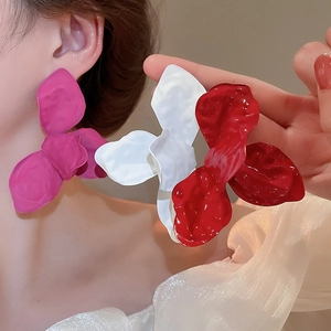 Detail of oversized matte flower earrings in magenta, white and dark red on model