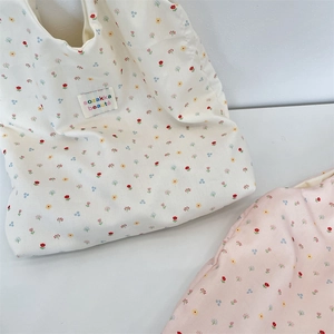 Detailed view of floral tote bags in beige and pink with small tulip prints and woven labels