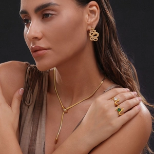 Close-up of 18k gold-plated snake jewelry set with green gemstones and white crystals