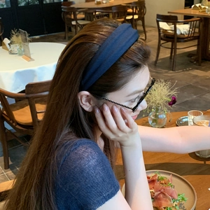 Navy blue knitted headband for women on model in a cozy cafe setting, high top style