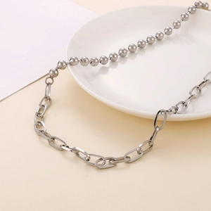 Détail macro du collier en acier titane argenté montrant la maille jante et perles
