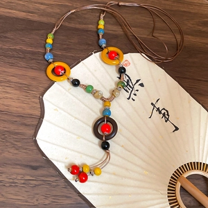 Detailed shot of ethnic ceramic bead necklace on a vintage fan with woven rope details