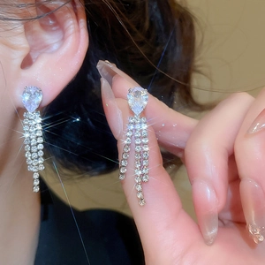 Dettaglio degli orecchini a nappa color argento con zirconi a goccia su modella