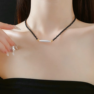 Detailed view of vintage black bead necklace featuring a white bar pendant with gold accents
