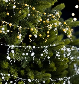 Close-up of white crystal pearl bead garland intertwined on green Christmas tree branches