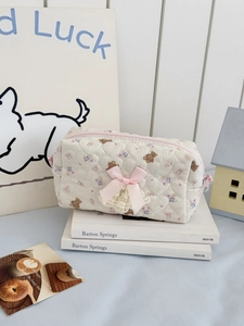 Detail of quilted bear cosmetic bag with pink ribbon bow and floral embroidery