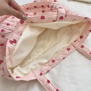 Internal detail of pink quilted tote bag showing cream lining and functional inner pocket