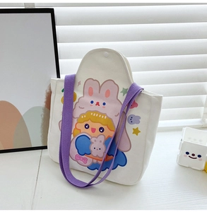 Detail of canvas tote bag with purple handles and cartoon girl print on desk