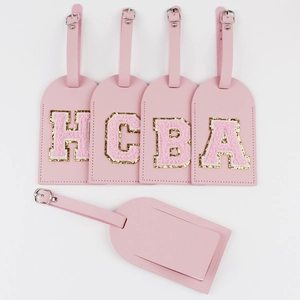 Macro detail of pink PU leather luggage tags featuring chenille letter patches and back slot