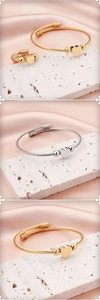 Detail of twisted steel cable heart bracelet and ring set in gold and silver finish